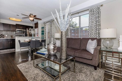 A modern living room with a glass coffee table and a brown couch.