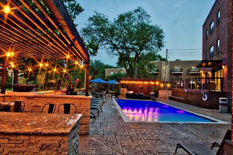 A pool area with a stone wall and a pergola.