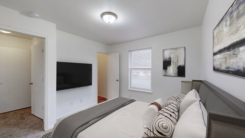A bedroom with a bed, a television, and two pictures on the wall.