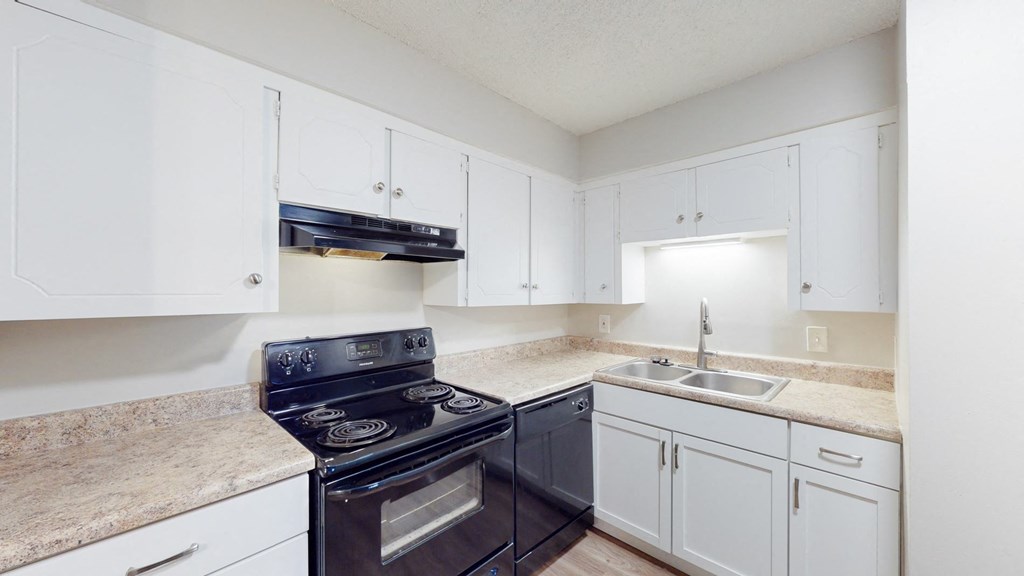 A kitchen with a black stove top oven and white cabinets.