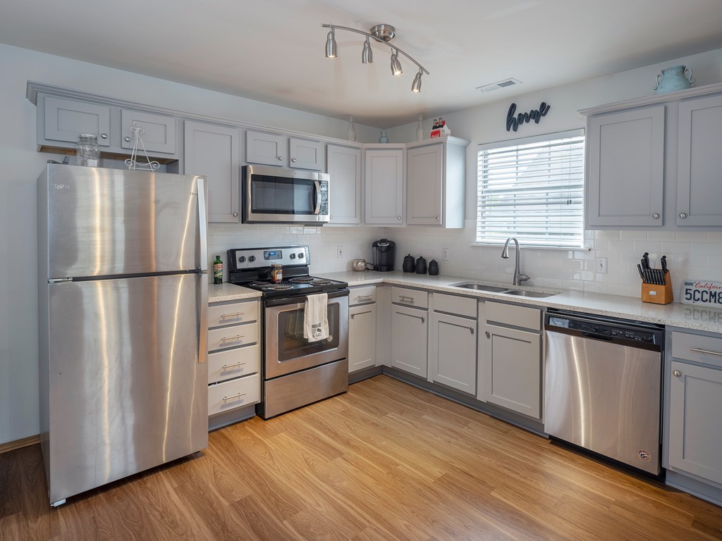 A kitchen with a stainless steel refrigerator, microwave, oven, and dishwasher.
