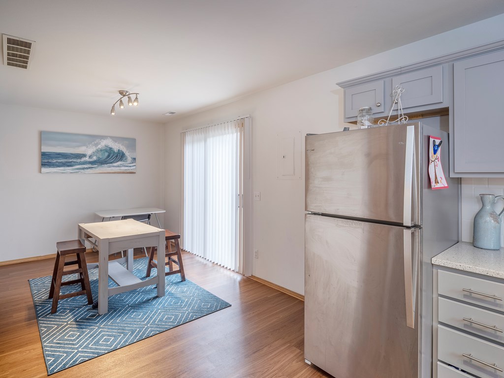 A kitchen with a refrigerator, table, and chairs.