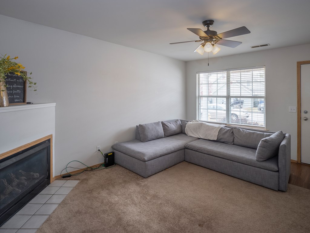 A living room with a grey couch and a fireplace.