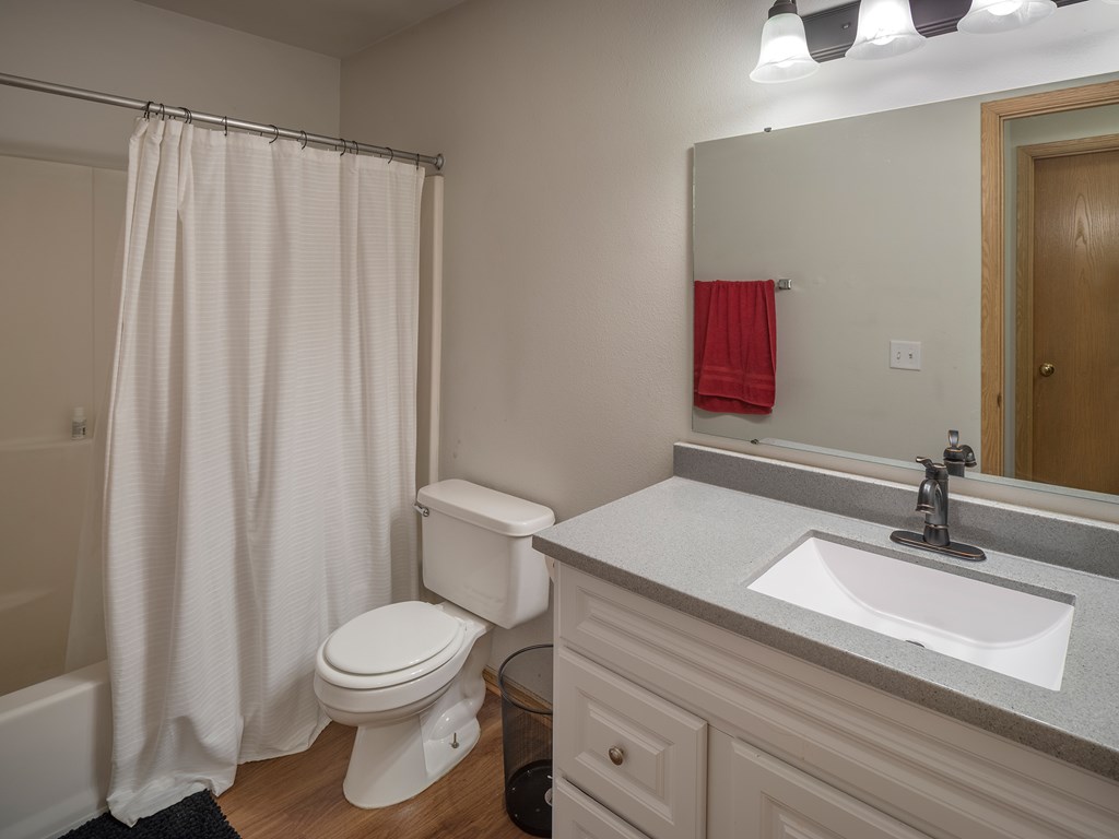 A white toilet with a white sink and a white shower curtain in a bathroom.