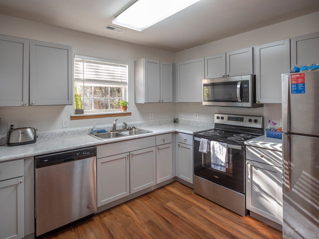 A kitchen with stainless steel appliances and wooden floors.