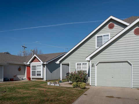 A house with a grey siding and a red door is shown.