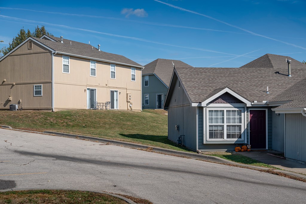 A house with a red door is situated on a street.