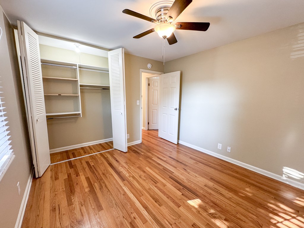 A room with a ceiling fan and wooden flooring.