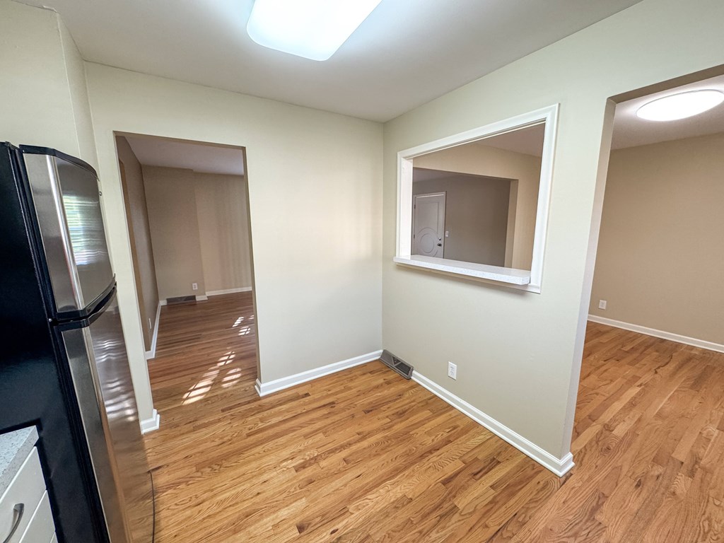 A kitchen with a black refrigerator and wooden floors.
