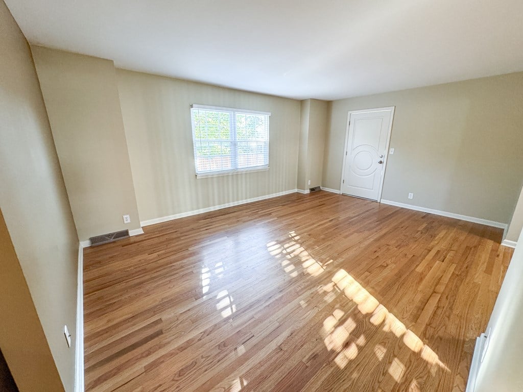 A room with wooden flooring and a window with blinds.