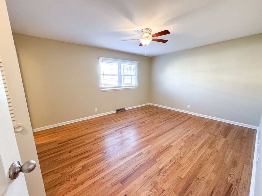 A room with wooden flooring and a ceiling fan.