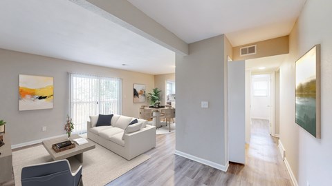 A living room with a white couch and a painting on the wall.