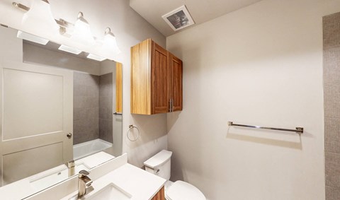 A white bathroom with a toilet, sink, and mirror.