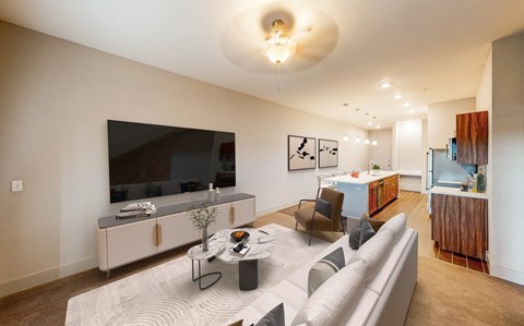A modern living room with a grey sofa, a coffee table, and a television on a cabinet.