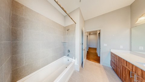 A bathroom with a tub and a wooden vanity.