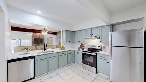 A kitchen with a refrigerator, sink, and oven.