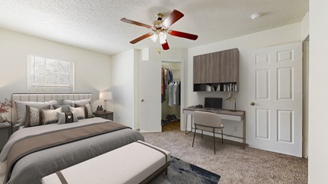 A bedroom with a bed, desk, and a ceiling fan.