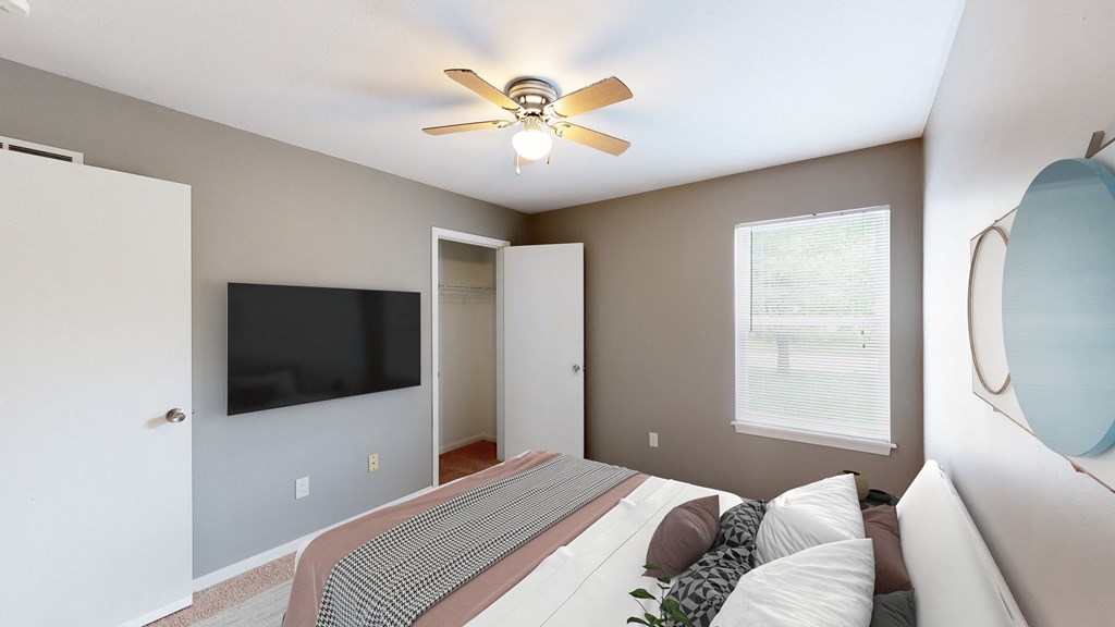 an empty bedroom with a large bed and a ceiling fan