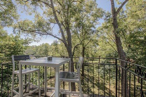 a table and chairs on a balcony with trees
