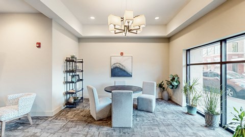 A room with a round table and chairs, a shelf, and a painting on the wall.