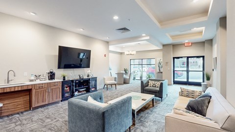 A modern living room with a kitchen area in the background.