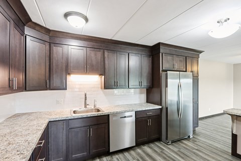 A kitchen with dark wood cabinets and a stainless steel refrigerator.