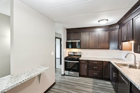 A kitchen with dark brown cabinets and a marble countertop.