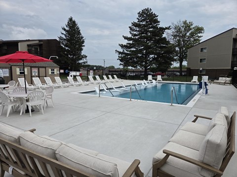 A pool area with chairs and umbrellas.