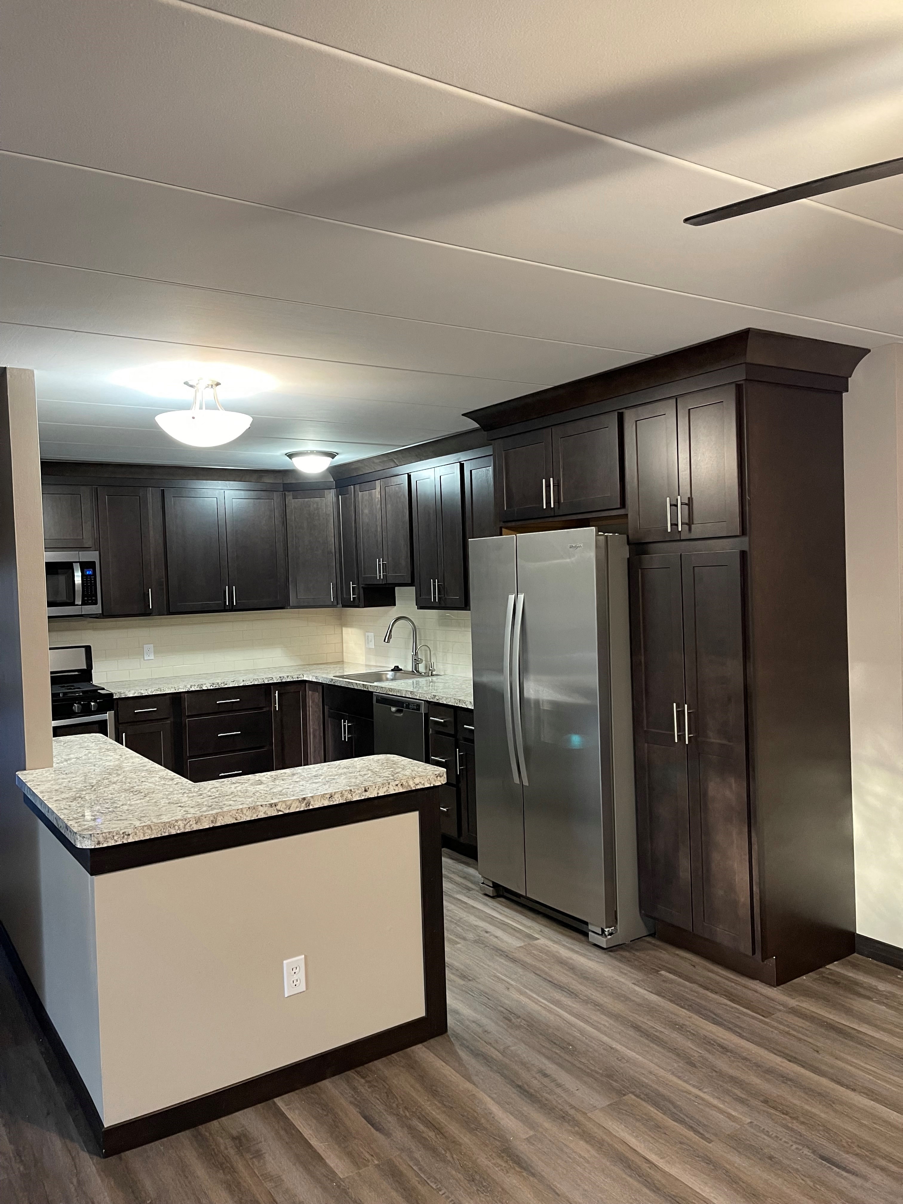 A kitchen with dark brown cabinets and a granite countertop.