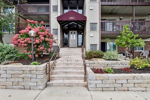 A building with a red awning and a stone wall in front of it.