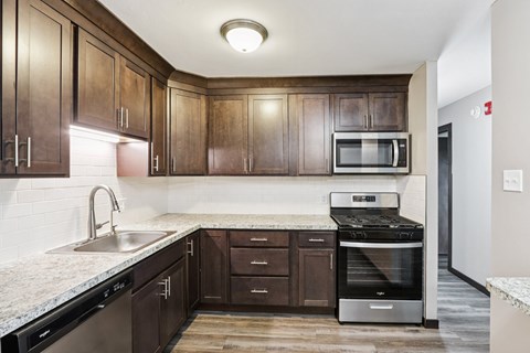 A kitchen with dark wood cabinets and stainless steel appliances.