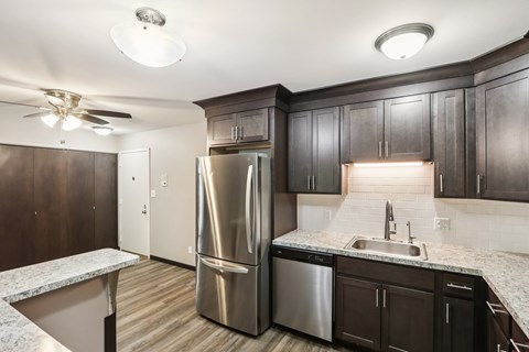 A kitchen with a stainless steel refrigerator and a marble countertop.