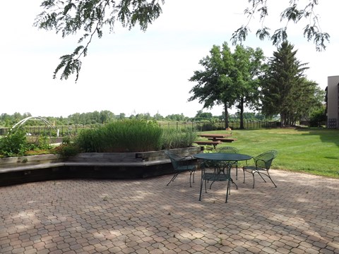 A patio with a table and chairs overlooks a grassy field.