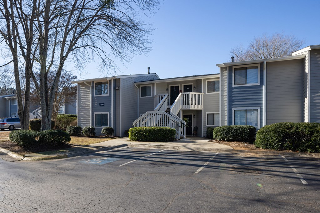 a gray apartment building with a staircase and a driveway