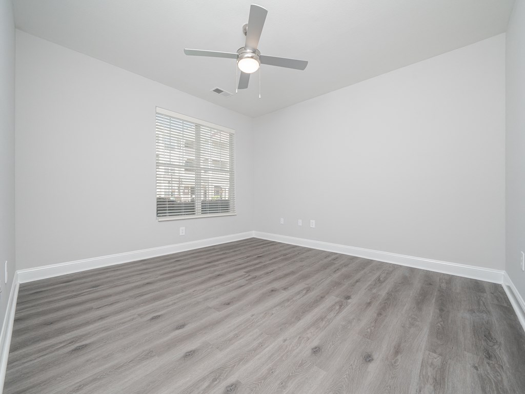 an empty living room with wood floors and a ceiling fan