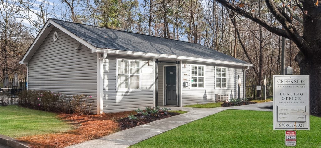 a small white house with a sign in front of it