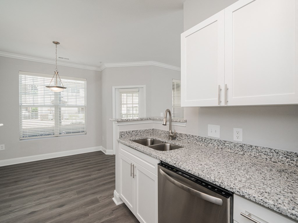 a kitchen with white cabinets and granite counter tops and a sink