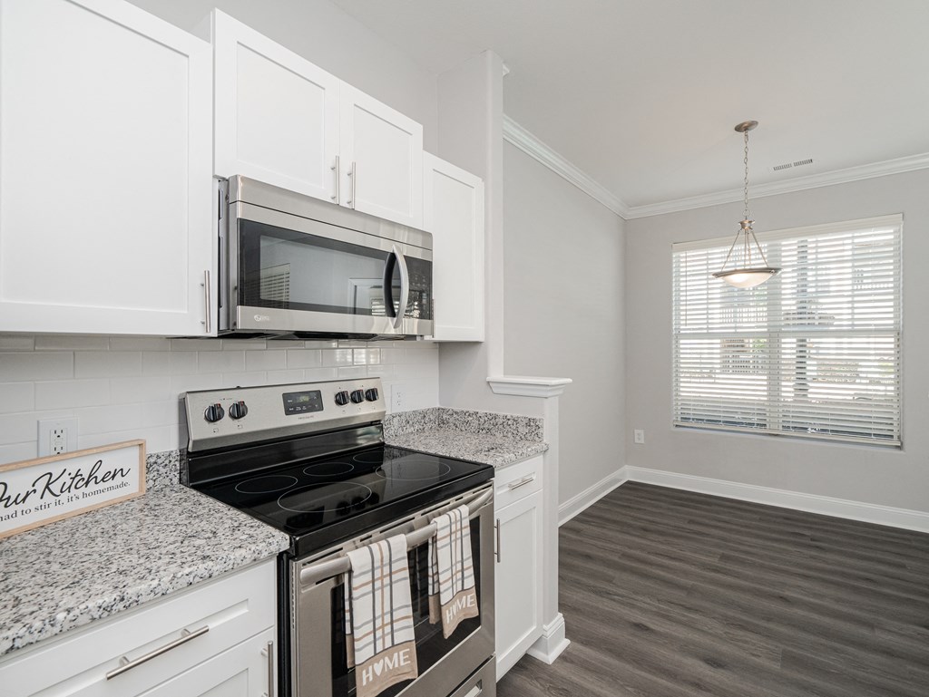a kitchen with white cabinets and a stove and a microwave