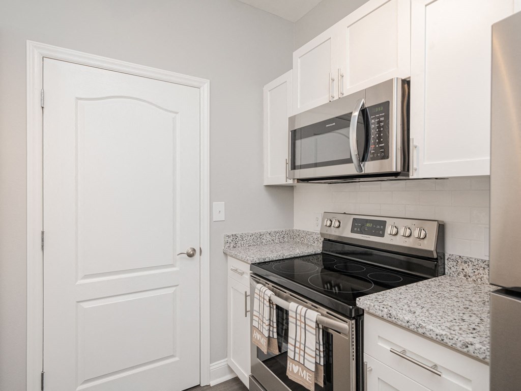 a kitchen with a stove microwave and white cabinets