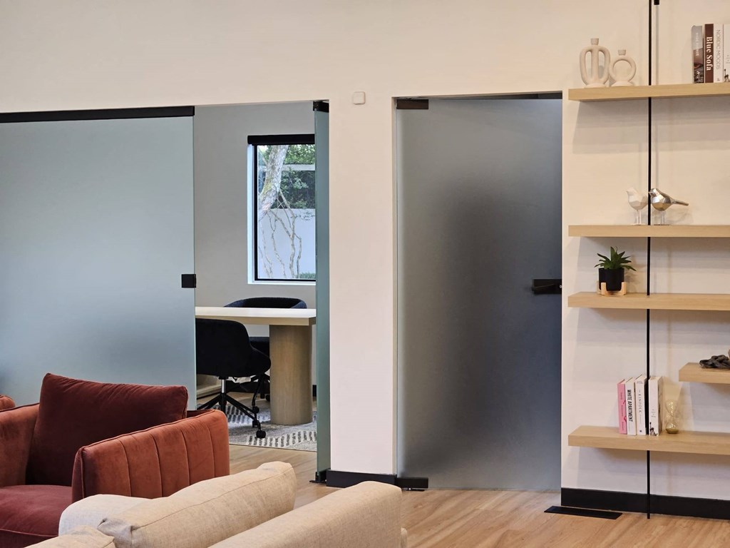 a living room with a desk and a door to a office