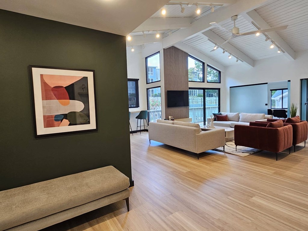 a living room with couches and chairs and a painting on a wall