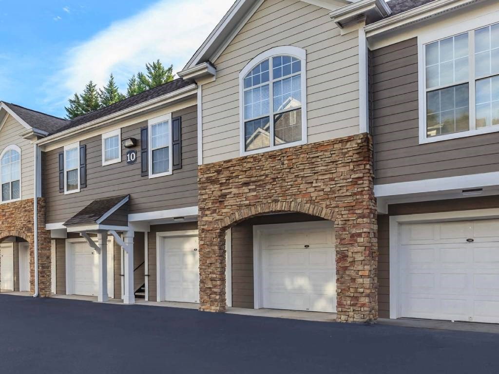 the front of a brick house with white garage doors
