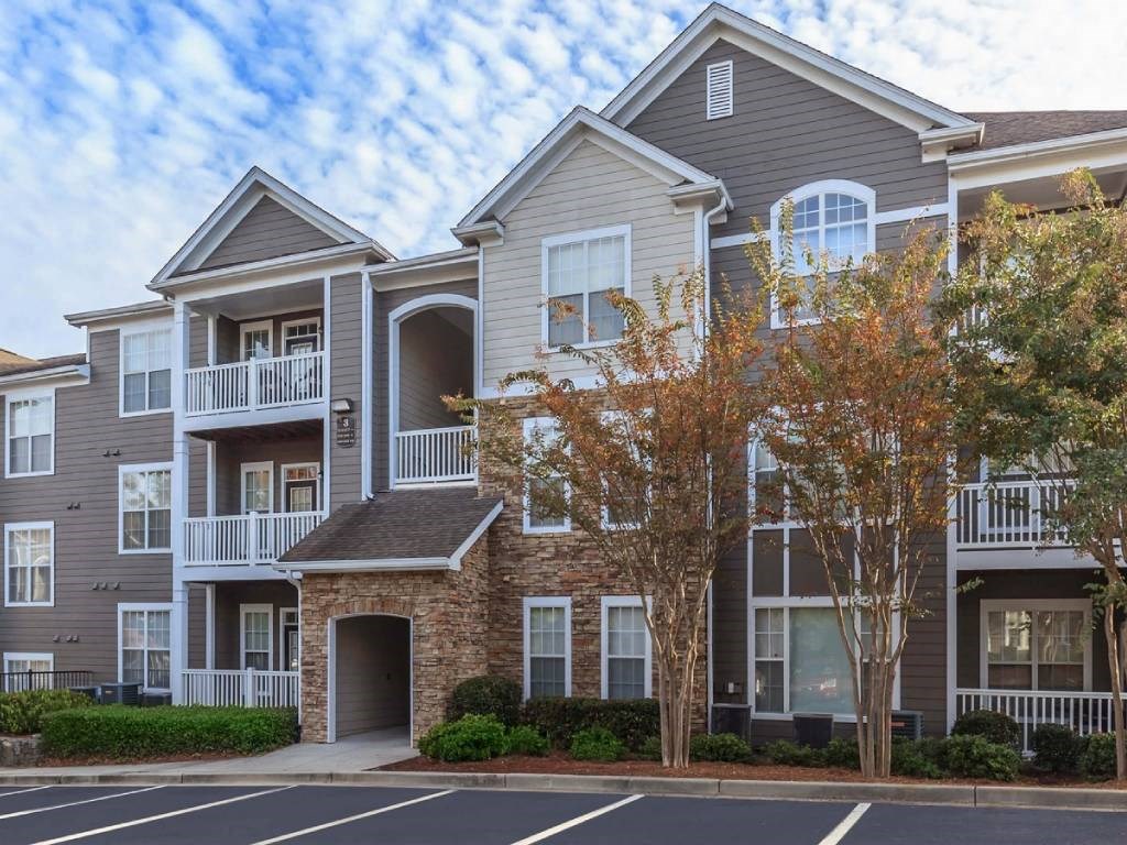 a building with two story apartments with balconies and trees