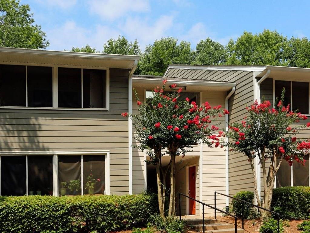 a gray house with red flowers in front of it