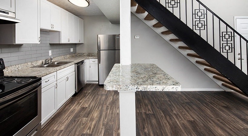a kitchen with a marble counter top and a staircase