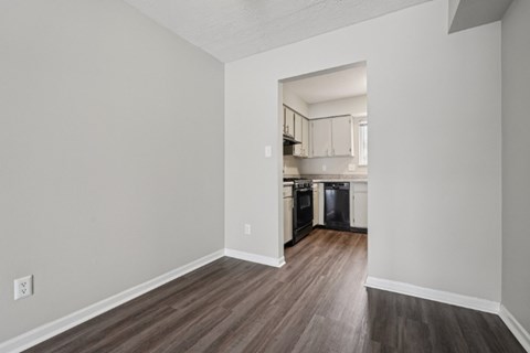 A kitchen with a refrigerator, oven, and cabinets is visible through an open doorway.