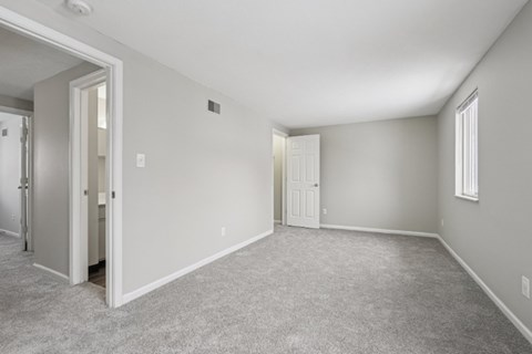 A spacious room with carpeted floor and white walls.