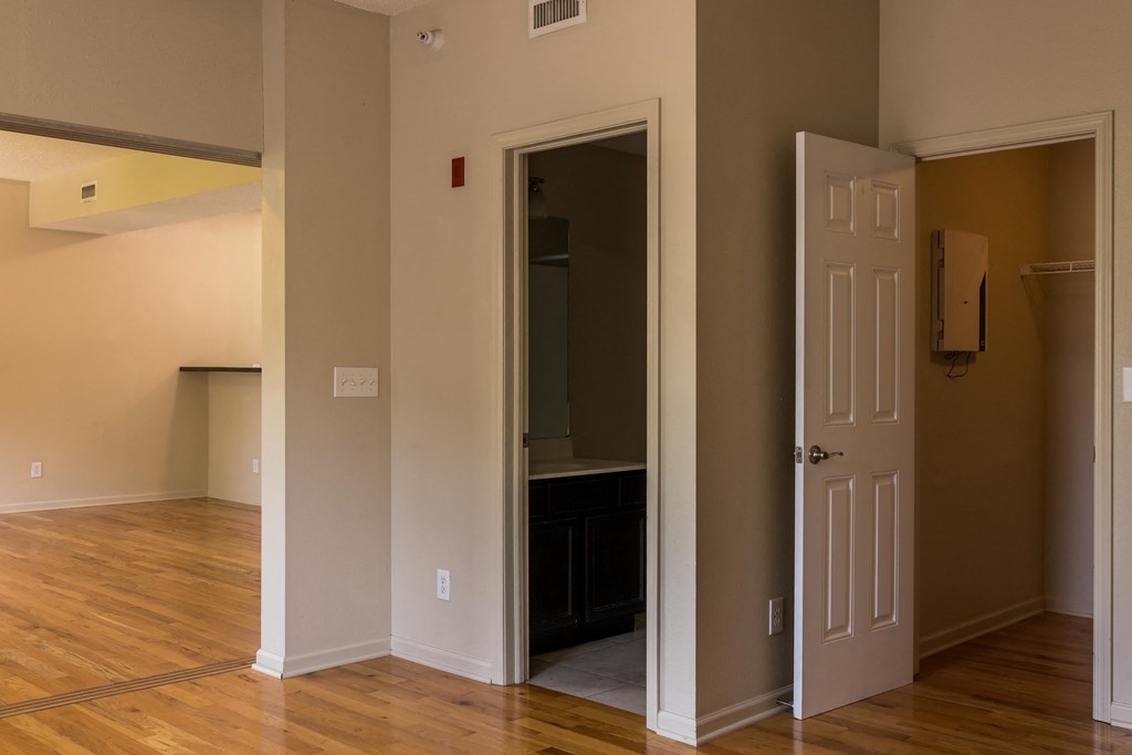 a living room with hardwood floors and a door that leads to a bathroom