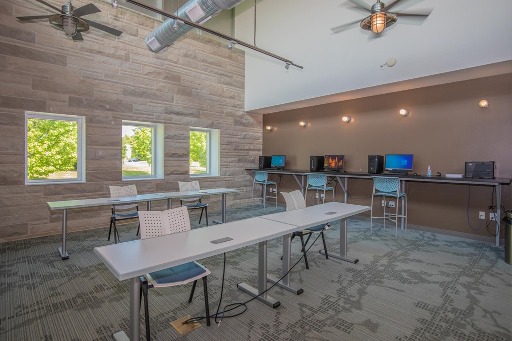 A room with tables and chairs and a ceiling fan.