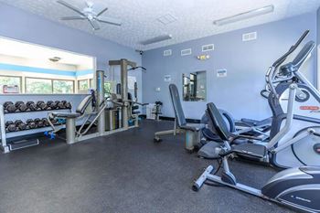 A gym with a variety of equipment including treadmills, weights, and exercise machines.
